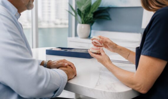 Mature patient discussing snap-in and traditional denture options with a dental professional in Brickell Miami